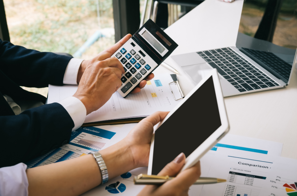 Business professionals analyzing reports and financial data with a calculator and tablet, showcasing cloud-based software for property management.