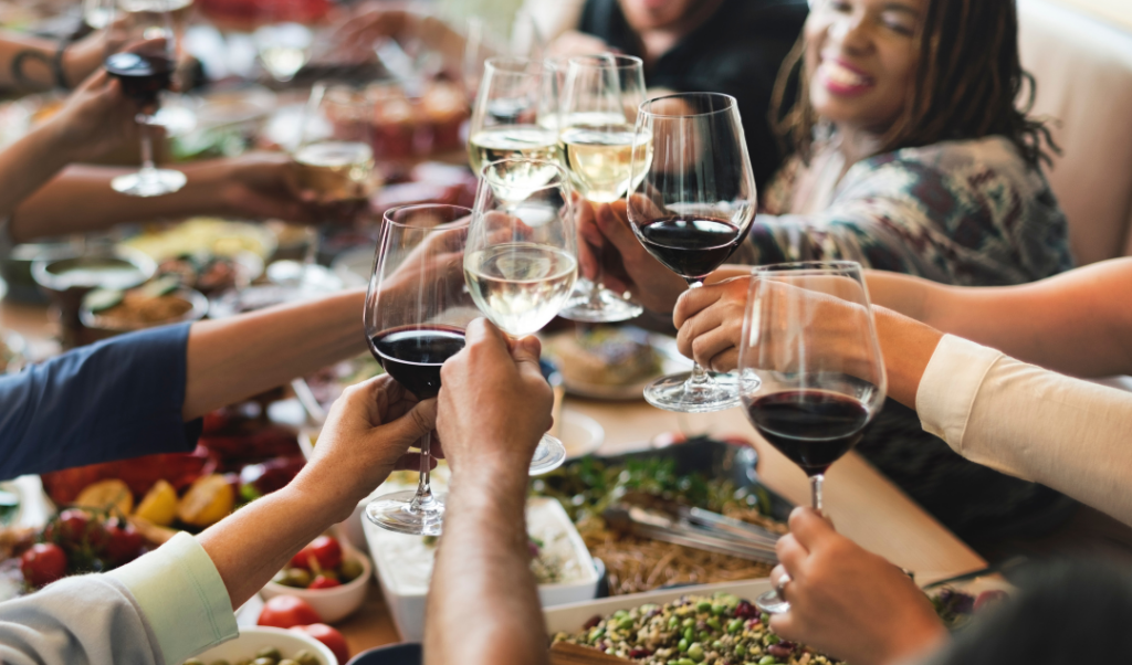Friends toasting with wine glasses at a lively dinner gathering, enjoying food and conversation.